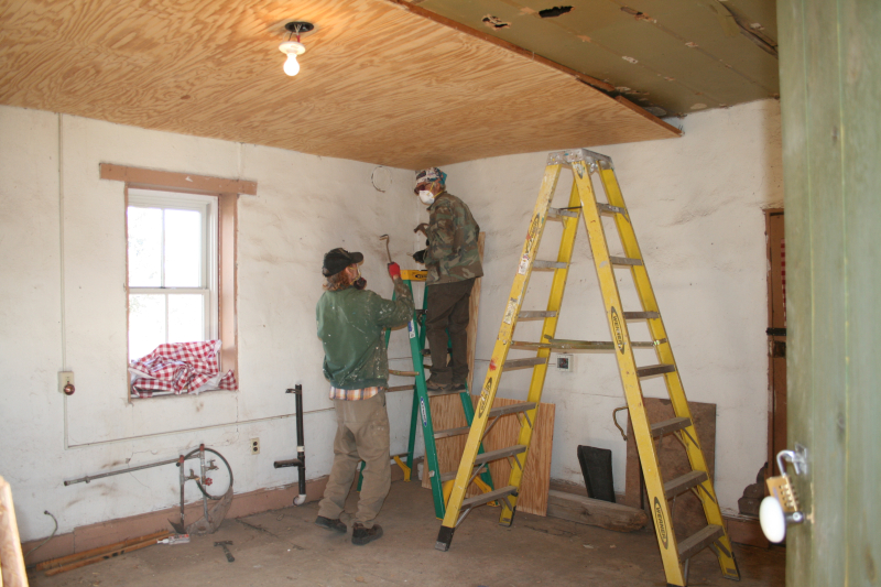 Two men with ladders performing ceiling demolition