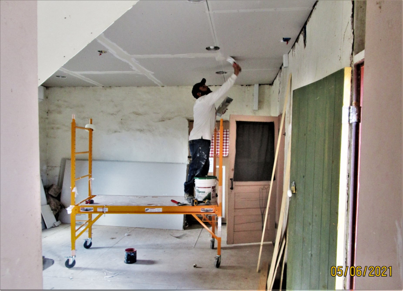man tapes and muds sheetrock ceiling on low scaffold
