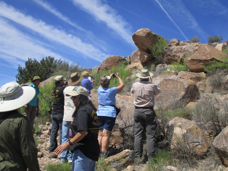 A group of people photographing a petroglyph panel